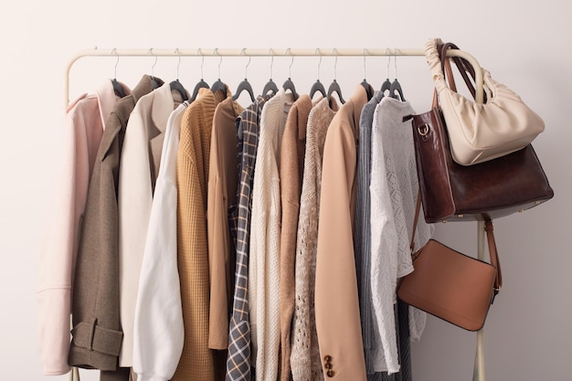 Ropa de otoño femenina en perchas en sala blanca