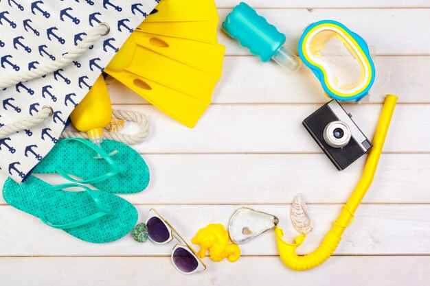 Ropa de playa y accesorios sobre un fondo blanco de madera