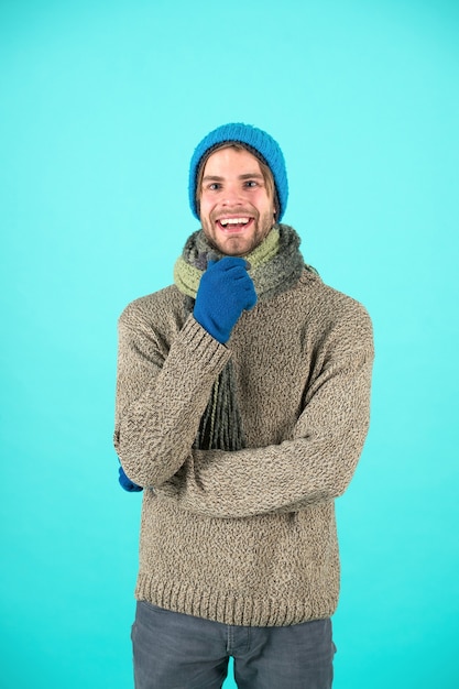 Ropa de punto de moda de invierno. Complementos tejidos como gorro y bufanda. Hombre en la temporada de moda de invierno de gorro y bufanda de punto. El hombre usa ropa de punto de fondo turquesa. Concepto de accesorios de invierno.