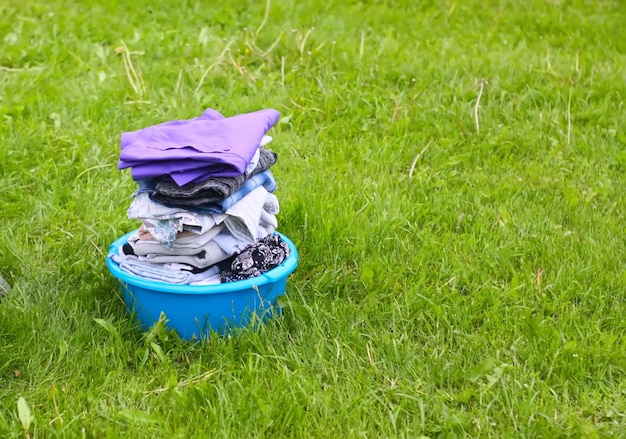 Ropa seca lavada de colores en un recipiente de plástico en el fondo de hierba verde