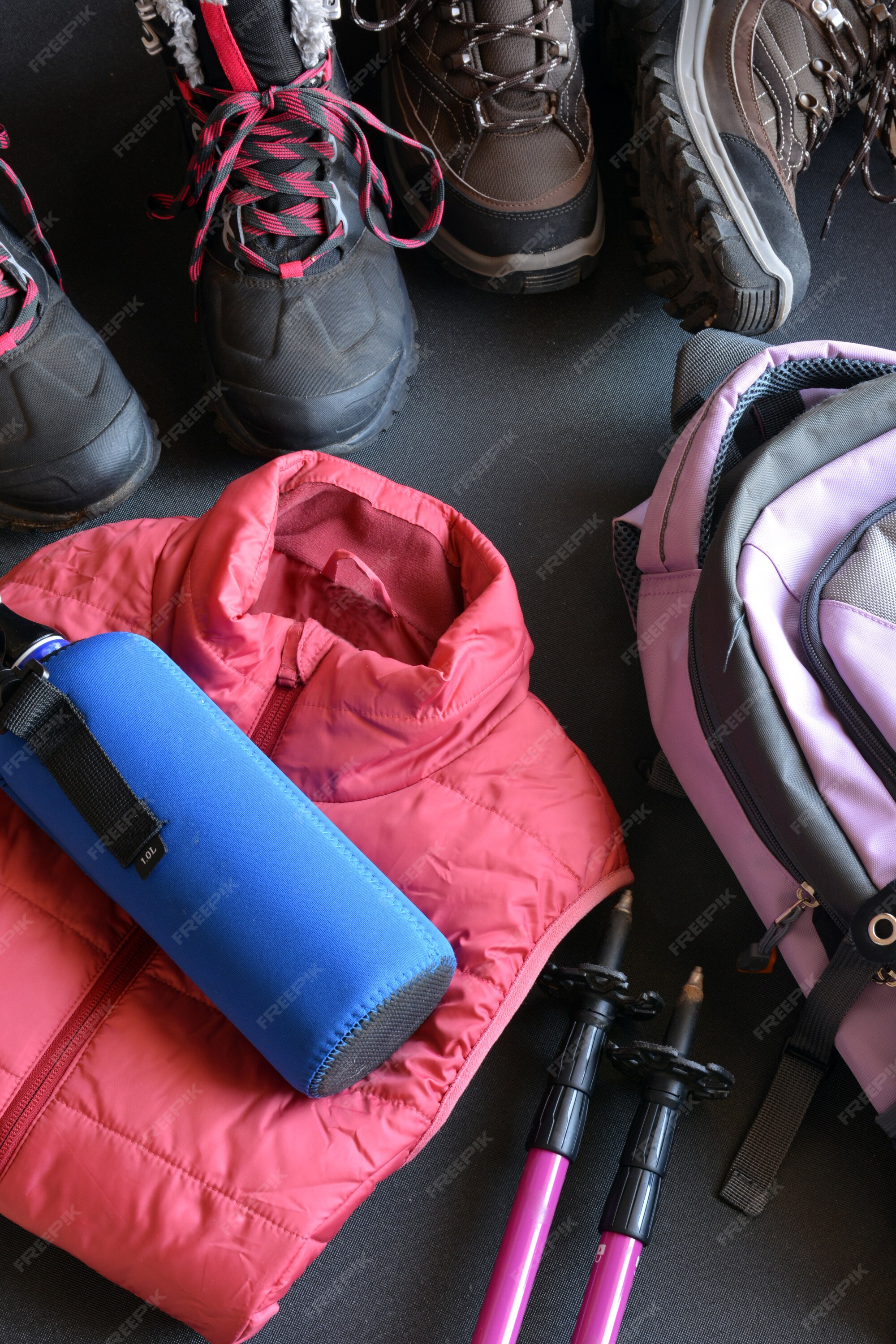 Ropa de senderismo para mujer y hombre, compuesta por botas, mochila, botella de agua y bastones. | Foto