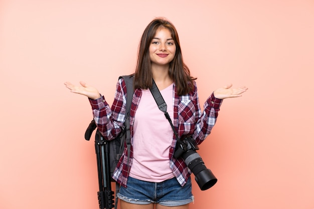 El rosa aislado muchacha joven del fotógrafo que tiene dudas con confunde la expresión de la cara