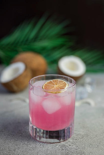 rosa alkoholischer Getränkecocktail mit Kokosnuss und Palmblatt