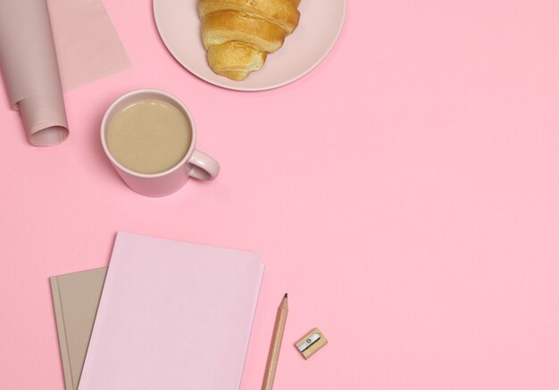 Rosa Anmerkung mit Bleistift und Bleistiftspitzer, Kaffeetasse, Kuchen auf rosa Hintergrund