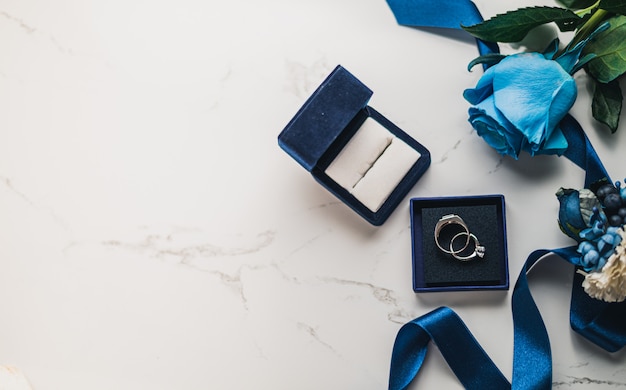 rosa azul, caja con anillos de boda y cinta
