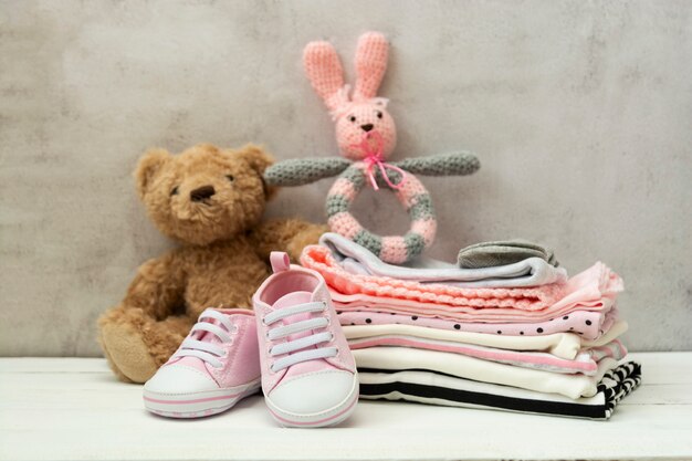 Rosa Babyschuhe, neugeborene Kleidung und Stofftiere. Mutterschafts-, Bildungs- oder Schwangerschaftskonzept mit Kopierraum.