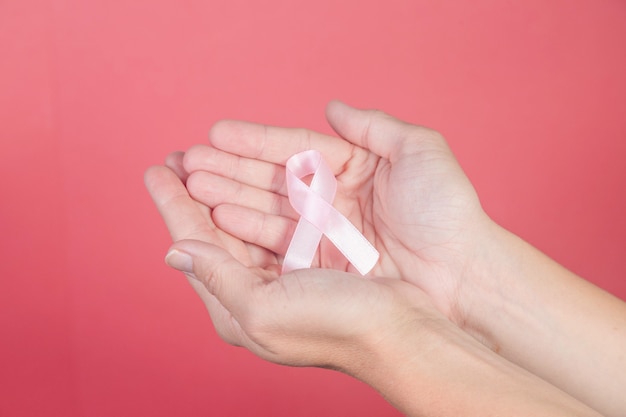 Rosa Band auf den Händen einer Frau. Brustkrebs, Gesundheits- und Medizinkonzept, Symbolband