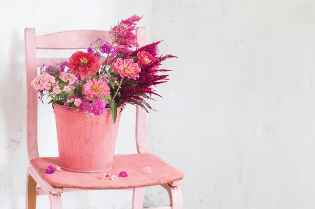 Rosa Blumen im Eimer auf weißem Tisch