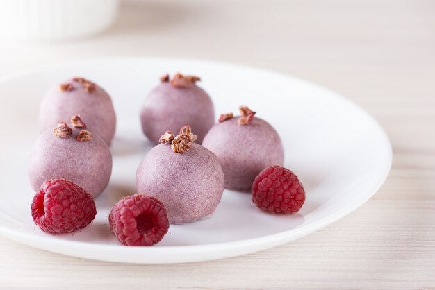 Rosa Bonbons mit Himbeeren auf einem weißen Teller zuckerfrei, gluten- und laktosefrei