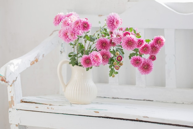 Rosa Chrysanthemen im Krug auf alter weißer Holzbank