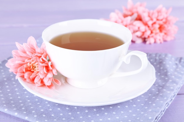 Rosa Chrysanthemen und Tasse Tee auf Holztisch