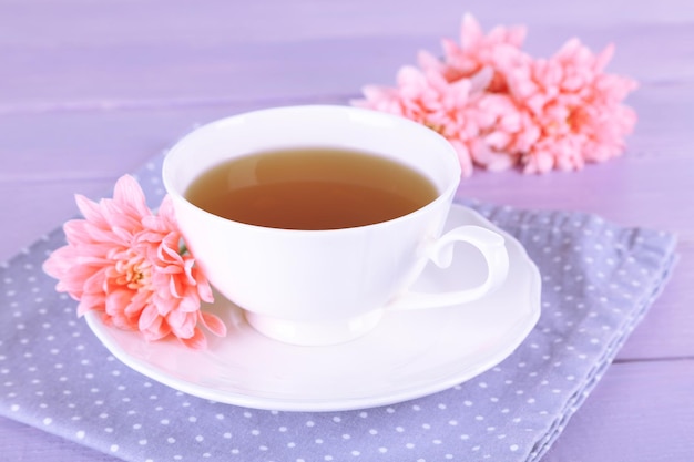 Rosa Chrysanthemen und Tasse Tee auf Holztisch