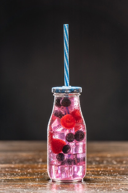 Foto rosa cocktail in einem hohen glas, verziert mit orange, himbeeren, erdbeeren und blaubeeren