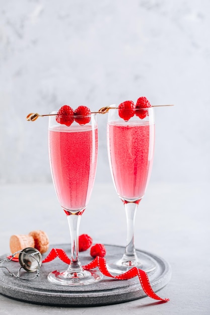 Rosa Cocktail mit Champagner oder Prosecco und frischen Himbeeren zum Valentinstag