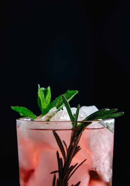 Rosa Cocktail mit Minze und Rosmarin auf schwarzer Hintergrundnahaufnahme