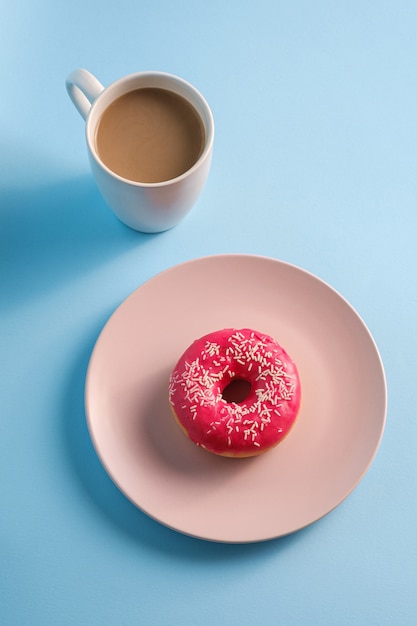 Rosa Donut mit Streuseln auf Teller nahe Tasse Kaffee