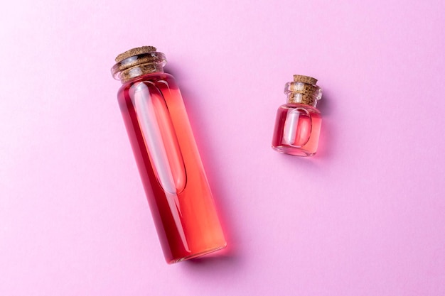 Rosa essencial rosa ou óleo cítrico de toranja na vista superior do fundo rosa
