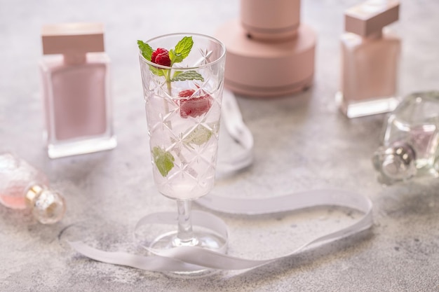 Rosa frischer Cocktail mit Himbeere und Minze auf dem Tisch mit Rosenflasche Parfümflasche