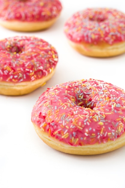 Rosa gefrosteter Donut mit bunten Streuseln auf Weiß