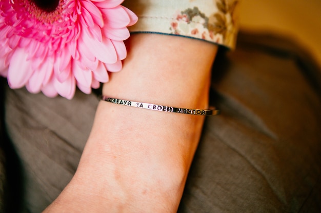 Foto rosa gerbera und die hand der frau mit metallarmband