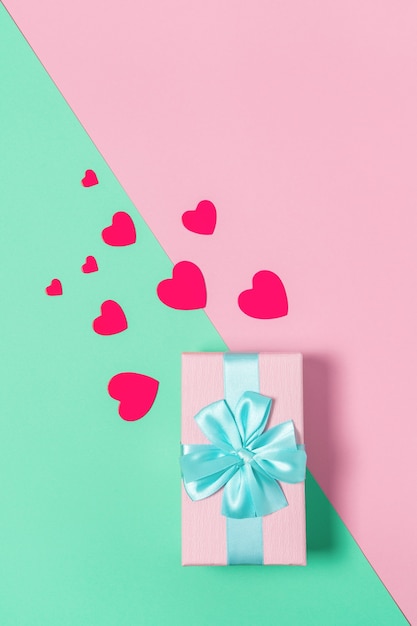 Rosa Geschenkbox mit blauer Schleife auf Pastell zweifarbigem Hintergrundrosa und Minze, Kopierraum, flache Lage. 8. März, 14. Februar, Geburtstag, St. Valentinstag, Mutter, Frauentag Feier Konzept. Vertikal