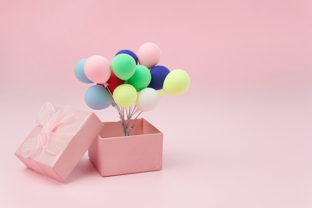 Rosa Geschenkbox mit buntem Ballon auf rosa Hintergrund