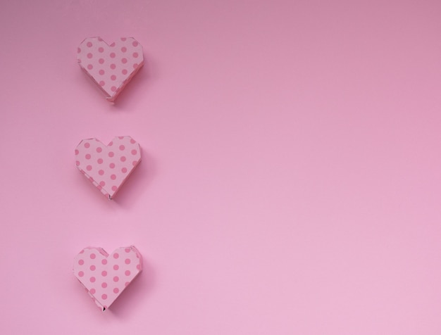 Rosa handgemachte Herz-förmige Geschenkboxen auf einem minimalen Konzept des Pastellrosahintergrundes