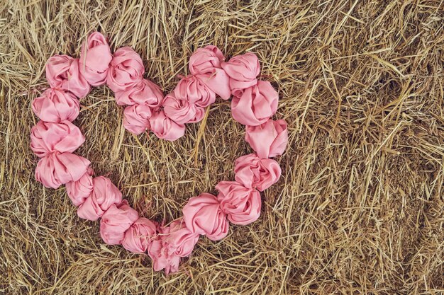 Foto rosa herz aus stoff auf einem strohhintergrund