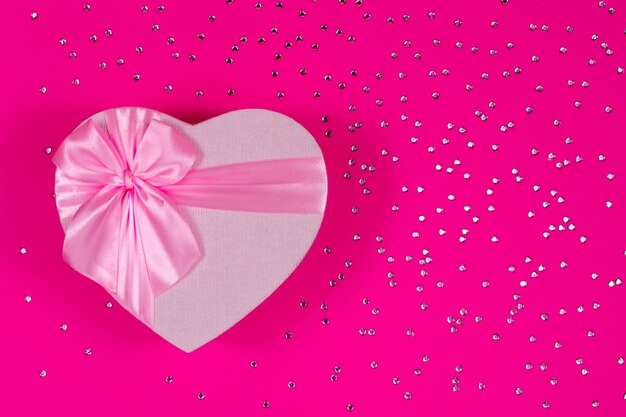 Rosa Herzbox mit Bogen auf rosa Hintergrund