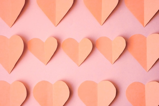 Rosa Herzen ausgeschnitten aus farbigem Papier auf einem rosa Hintergrund, Draufsicht. Monochrom gefärbtes Valentinstagkonzept.