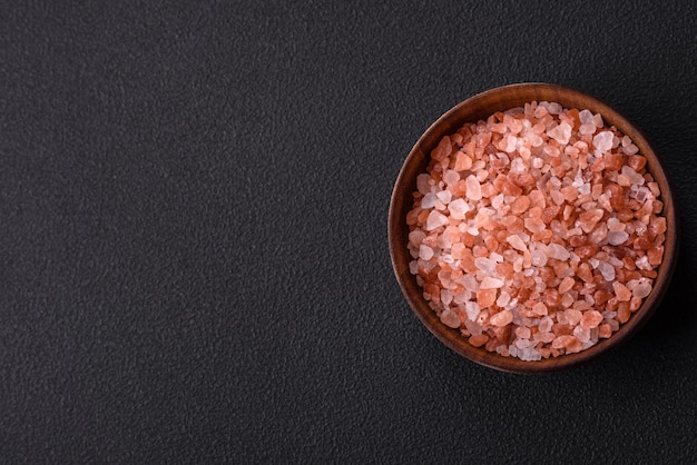 Foto rosa himalaya-salz in einer holzschale auf dunklem betonhintergrund gewürze und zusatzstoffe in der küche