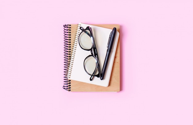 Rosa Hintergrund mit Notizblock, Bürobrille, Stift, Platz für Text. Trendkonzept.