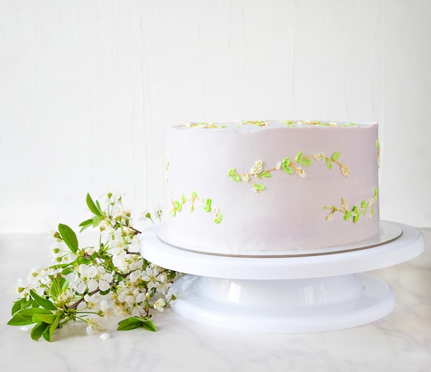 Rosa Hochzeitstorte auf einem Ständer mit Kirschblütenzweigen. zarte Dekoration auf Kuchen.