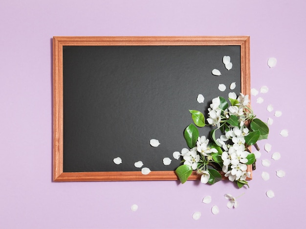 Rosa horizontaler Hintergrund mit Frühlingsblumen auf der schwarzen leeren Tafel mit Platz für Text