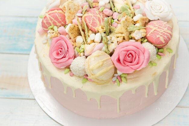 Rosa Kuchen mit Blumen und Cupcakes auf einem weißen Teller