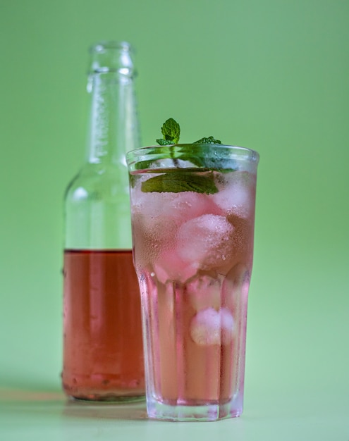 Rosa Limonade oder Cocktail in Glas und flaschengrüner Pastelloberfläche