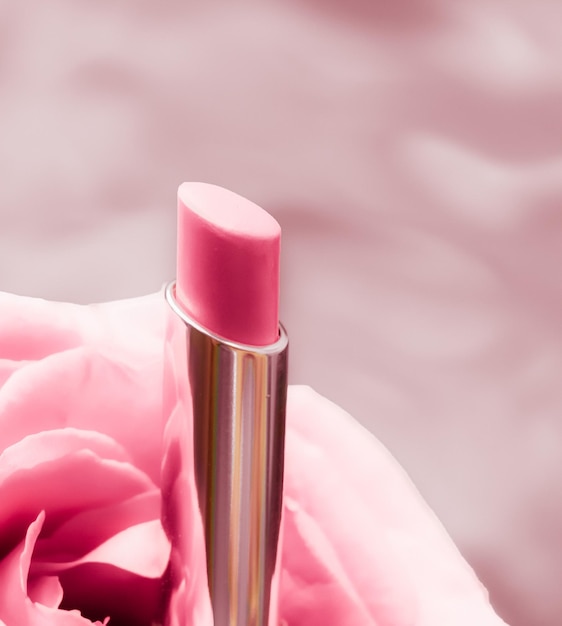 Rosa Lippenstift und Rosenblüte auf flüssigem Hintergrund, wasserdichtes Glamour-Make-up und Lipgloss-Kosmetikprodukt für Luxus-Beauty-Marken-Urlaubsdesign