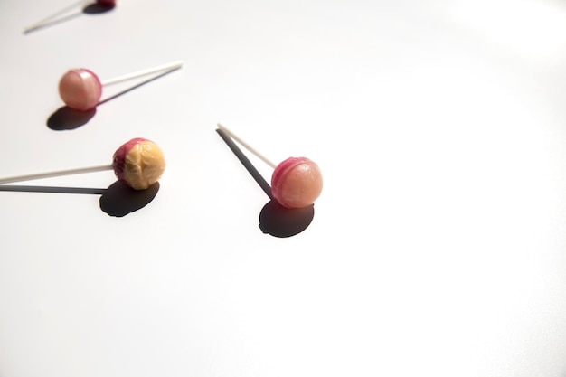 Rosa Lolipop-Bonbons liegen auf einem weißen Hintergrund Seitenansicht