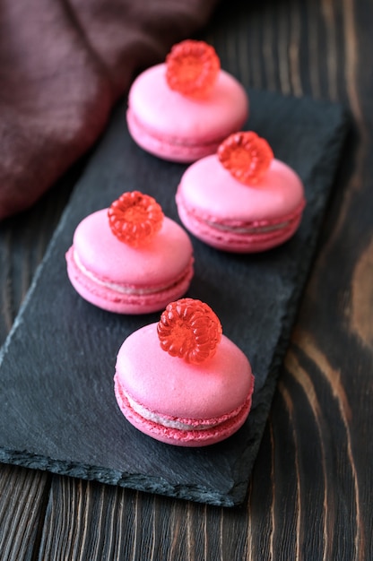 Rosa Macarons - süßes Konfekt auf Baiserbasis, dekoriert mit frischen Himbeeren