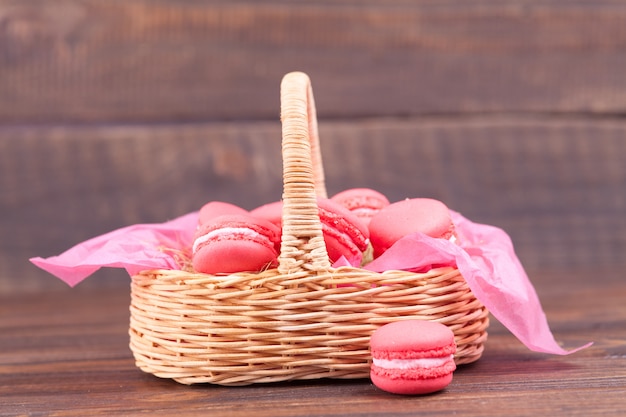 Foto rosa makronen in einem weidenkorb auf einem dunklen hölzernen.