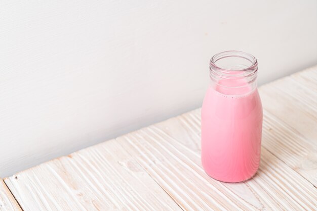 rosa Milch oder Erdbeermilch in der Flasche auf Holz