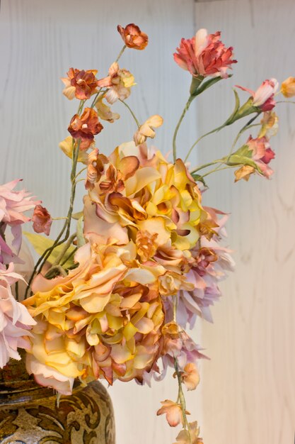 Rosa Nelken und orangefarbene Chrysanthemen in einem weißen Vase.