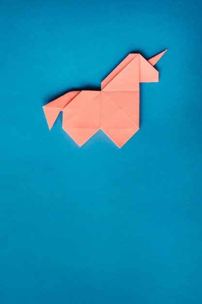 Rosa Origami-Einhorn auf blauem Hintergrund