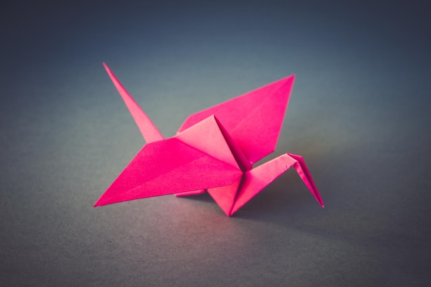 Rosa Papierkranich-Origami lokalisiert auf einem grauen Hintergrund