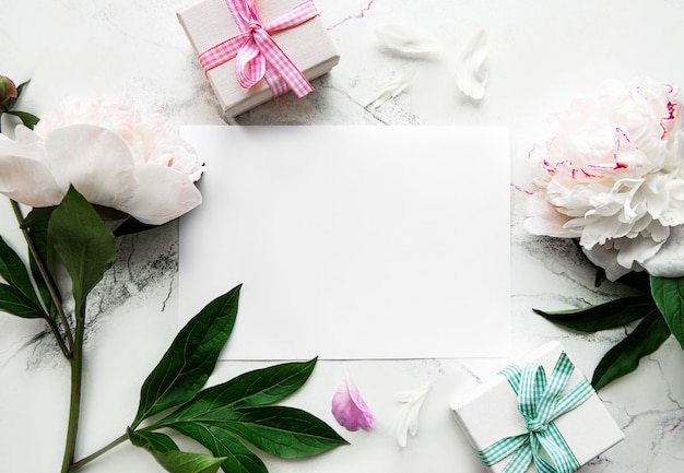 Rosa Pfingstrosen mit leerer Karte und Geschenkbox auf weißem Hintergrund