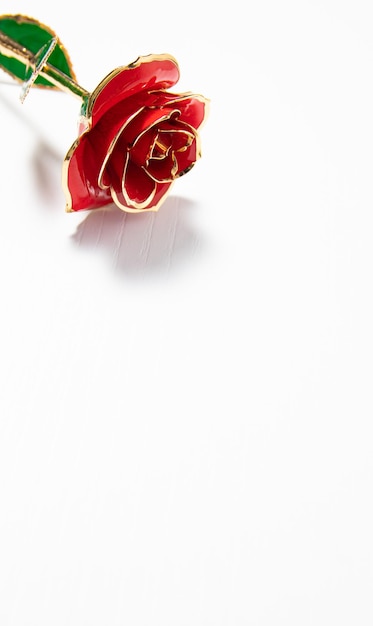 Foto una rosa roja con adornos dorados y un fondo blanco.