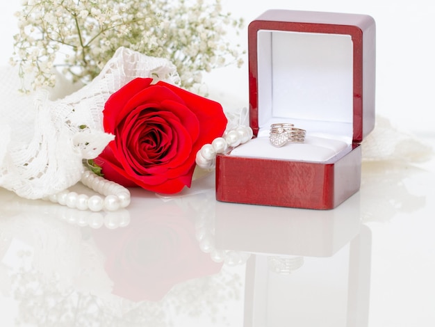 Rosa roja y anillo de diamantes en la mesa de cristal para una novia