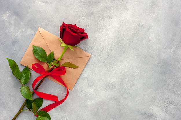 Rosa roja con cinta y carta de amor.