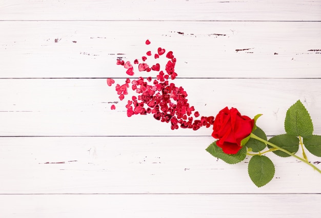 Foto rosa roja y corazones sobre fondo de madera