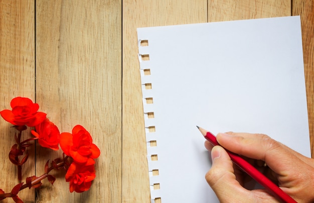 Rosa roja y papel para mensaje sobre fondo de madera